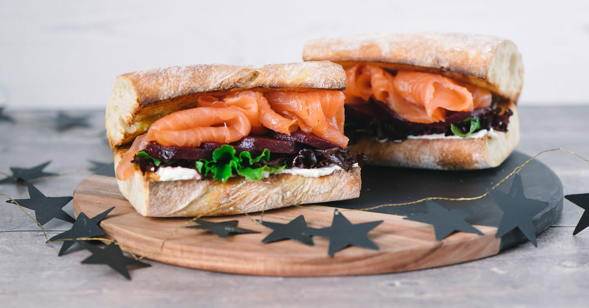 Due panini con salmone affumicato, barbabietole e lattuga su tagliere con stelle.