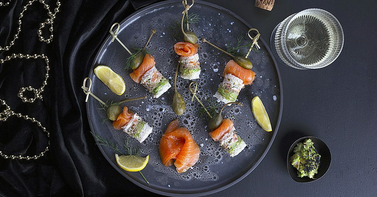 Canapés di salmone con capperi e limone su piatto scuro.