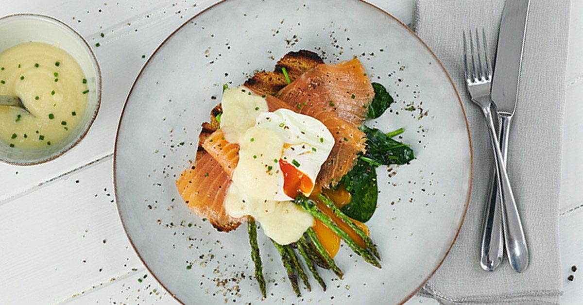Uova in camicia su salmone affumicato, spinaci e asparagi, con salsa olandese.