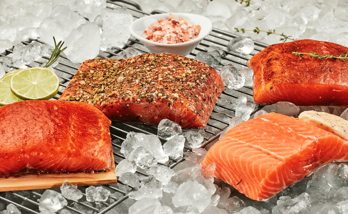 Filetti di salmone crudi conditi e cotti su un letto di ghiaccio con lime e sale.