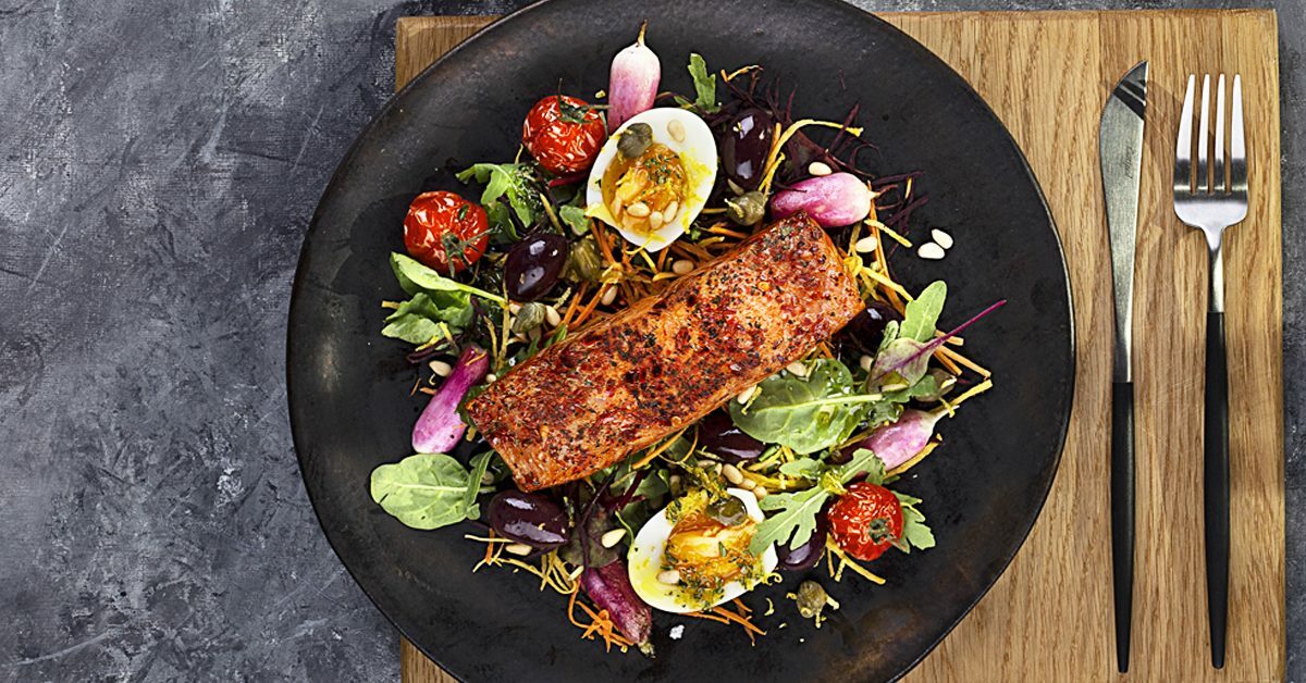 Filetto di salmone su insalata con uova, pomodorini e olive.