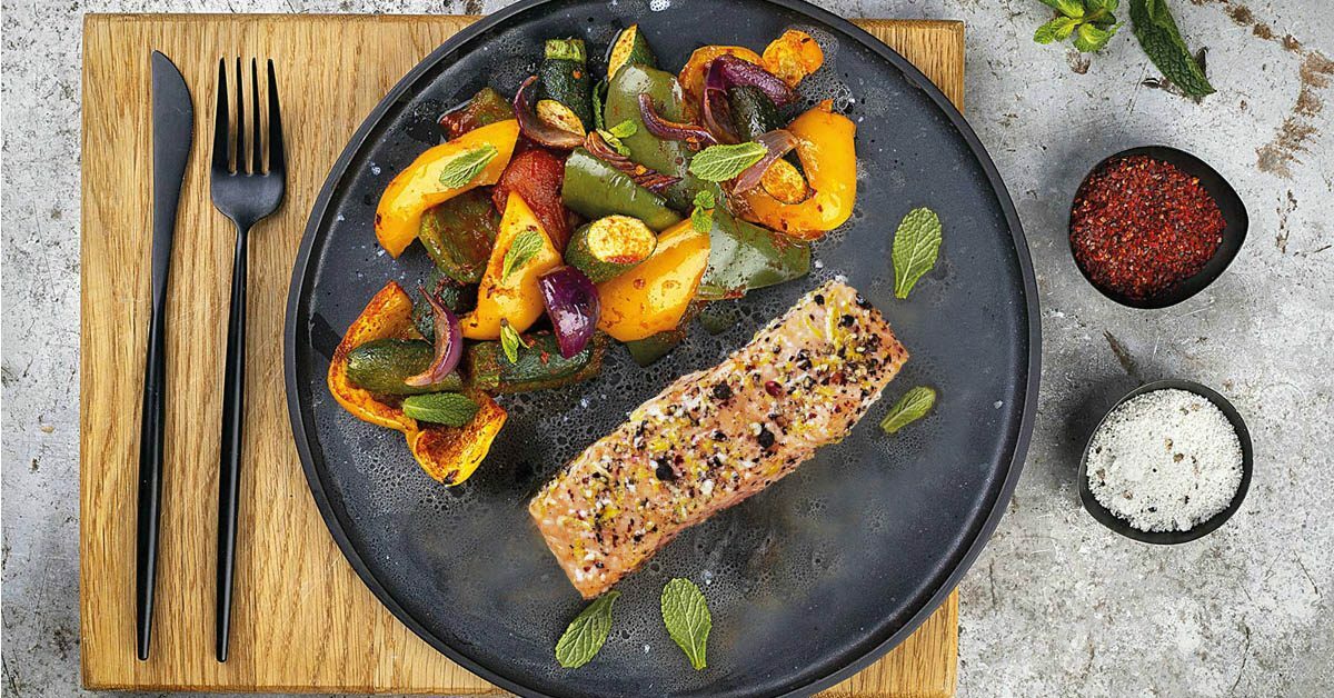 Salmone con verdure miste al forno, guarnito con menta fresca.