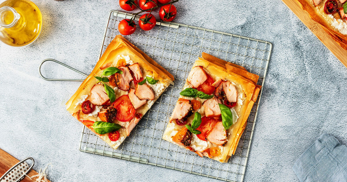 Focaccia con salmone, pomodorini e basilico su una gratella.