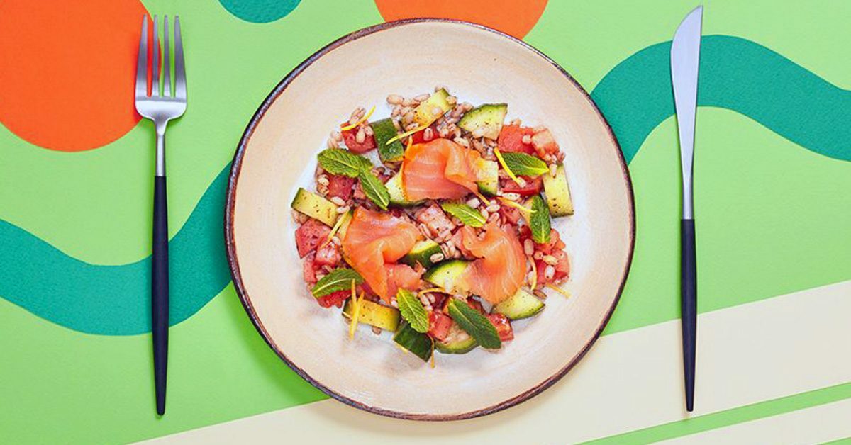Insalata fresca con salmone affumicato, pomodori, cetrioli e menta su un piatto.