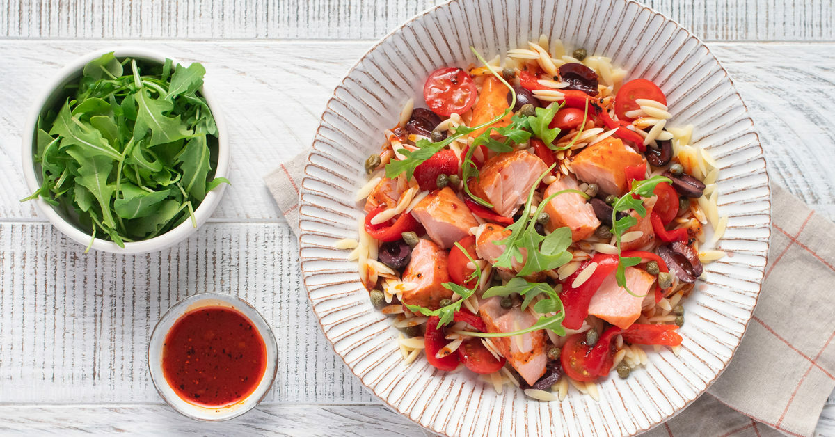 Insalata di orzo con salmone, pomodorini, olive e rucola.