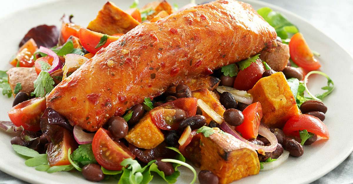 Filetto di salmone speziato su insalata di fagioli, pomodori, patate dolci e verdure.