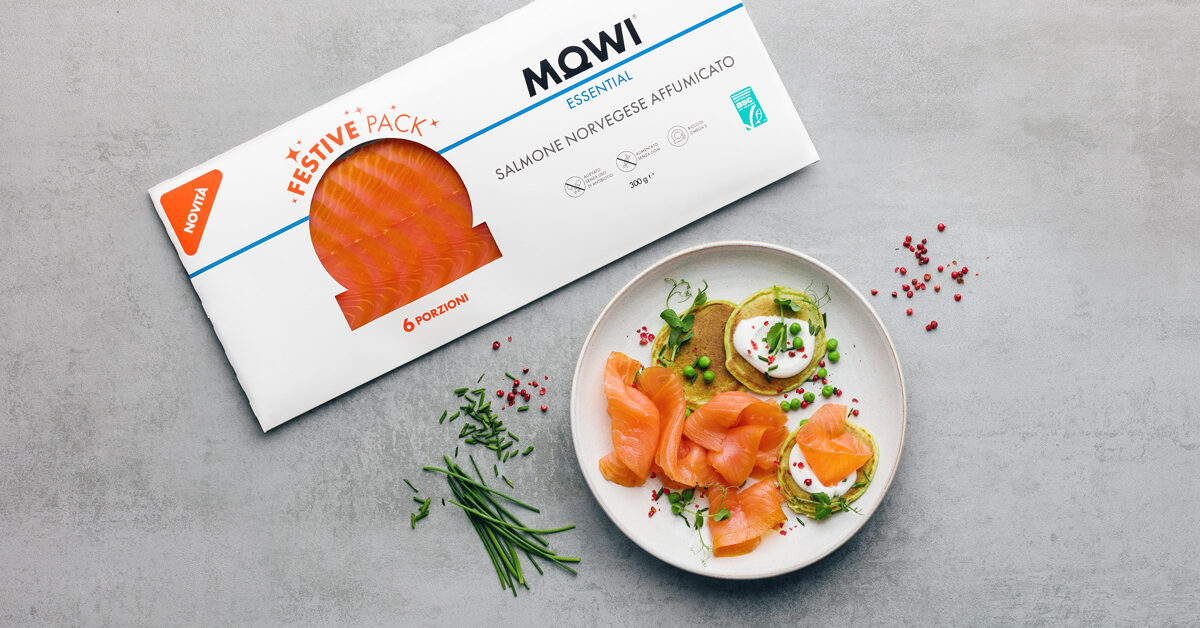 Confezione di salmone norvegese affumicato Mowi su piatto con pancake verdi e panna.