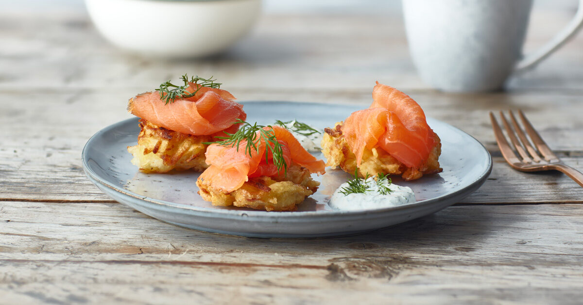 Frittelle di patate croccanti con salmone affumicato e aneto su un piatto.
