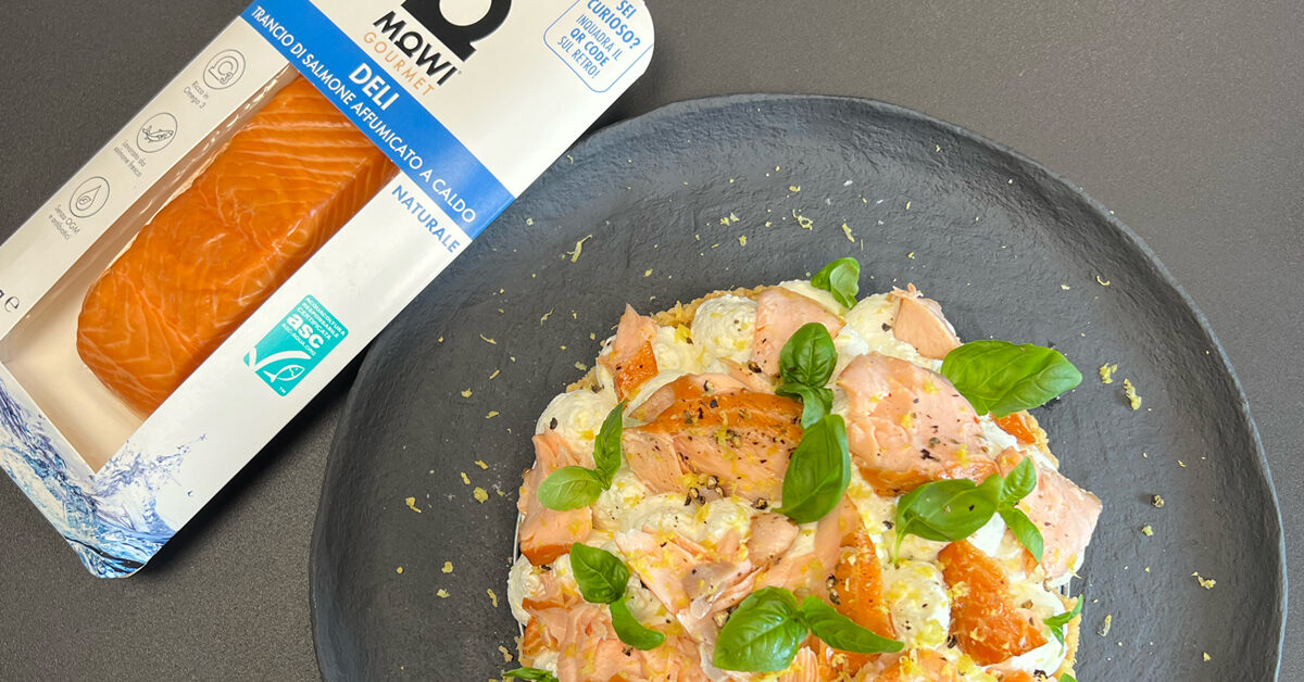 Trancio di salmone affumicato su torta con formaggio spalmabile e basilico.