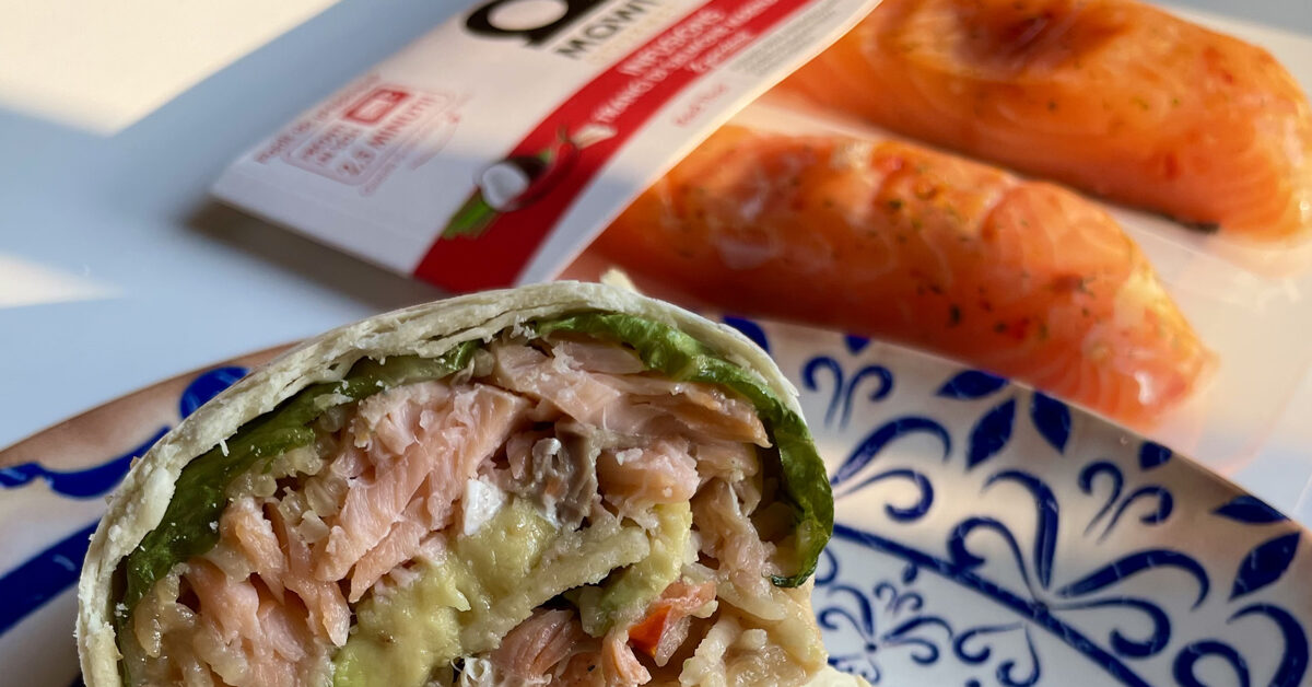 Wrap di salmone con avocado e lattuga su piatto blu e bianco con salmone in confezione sul retro.
