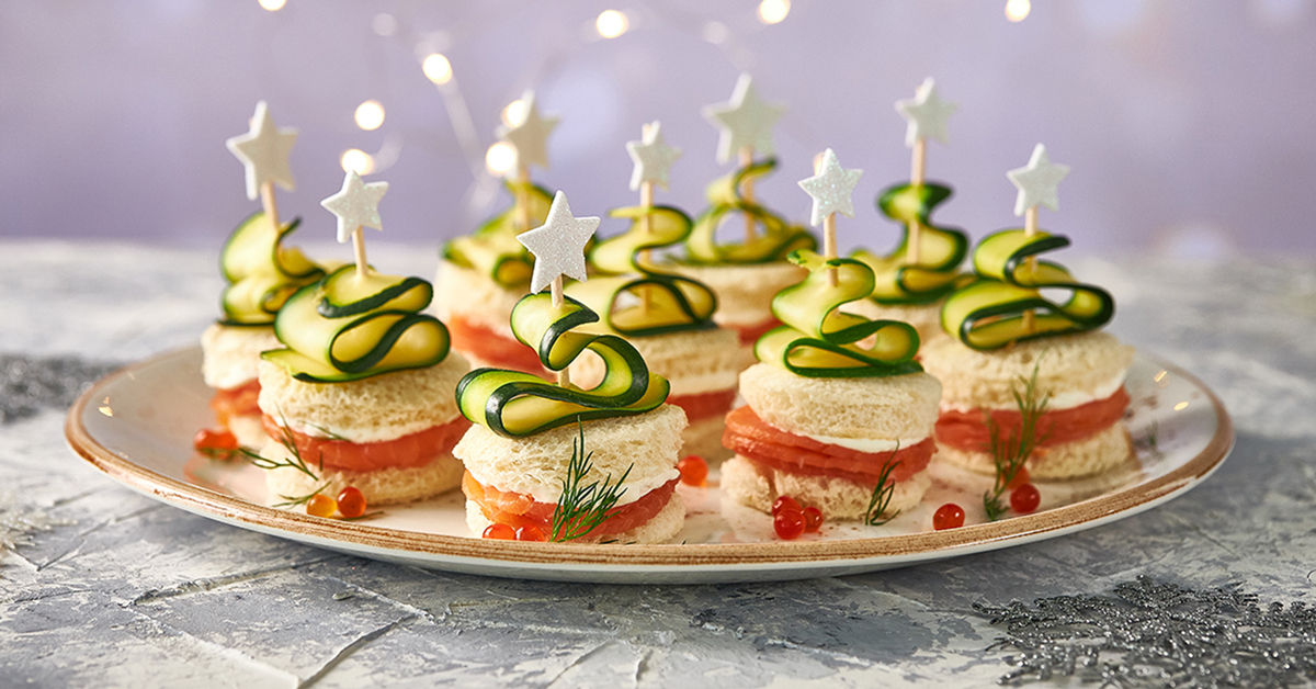 Alberelli natalizi salati con zucchine, salmone e stelle, su un piatto.