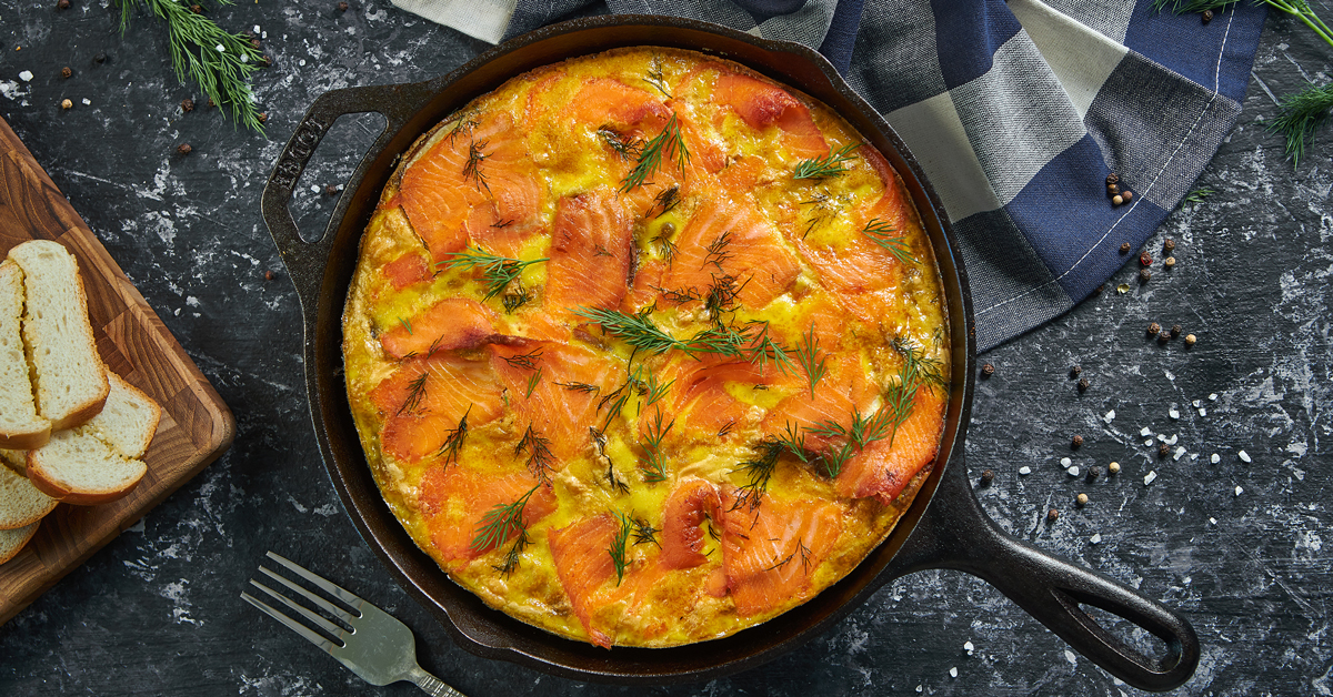 Frittata di salmone con aneto in padella, servita con pane tostato.