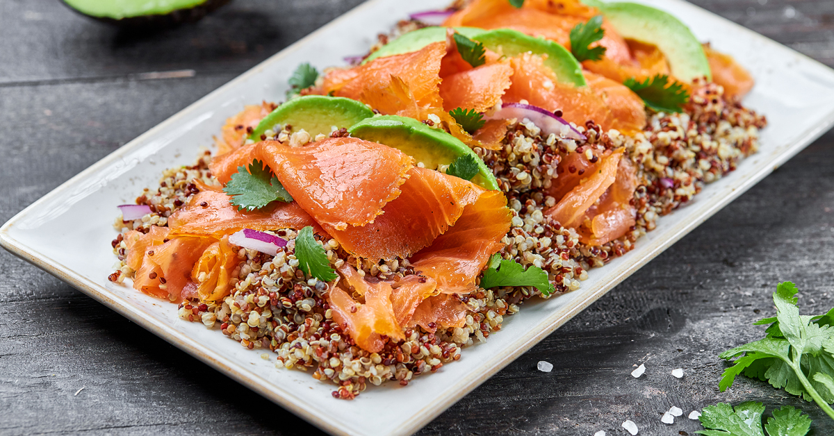 Insalata di salmone affumicato, quinoa e avocado su un piatto bianco.
