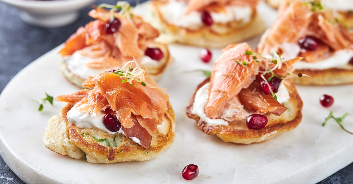 Mini pancake con salmone affumicato, crema, melagrana e germogli.